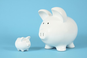 Two piggy banks, one big and one small, on a bright blue background